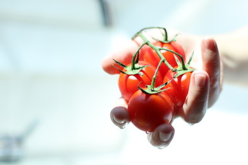 Frau wäscht rote kleine Tomaten in der Küche.