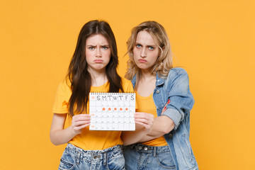 Displeased young women girls friends in denim clothes posing isolated on yellow background....