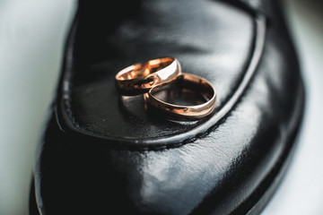 Close up of wedding rings on a black leather shoe
