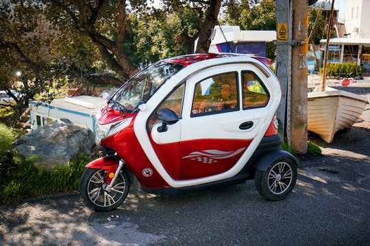 Cute small tricycle electric car parked near the asphalt road