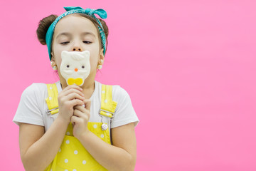 Child licking a sweet lollipop. Pink background