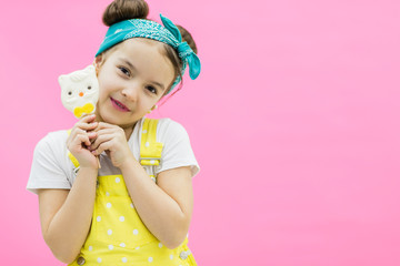Little girl holding sweet lollipop candy. Pink background