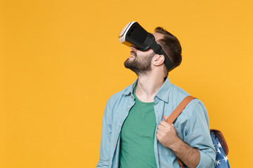 Smiling young man student in casual clothes with backpack isolated on yellow background studio portrait. Education in high school university college concept. Mock up copy space. Watching in headset.