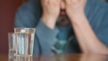 man holds hands on face in depression alcohol addiction