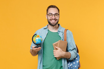 Smiling young man student in casual clothes glasses with backpack isolated on yellow wall background studio portrait. Education in high school university college concept. Hold world globe, books.