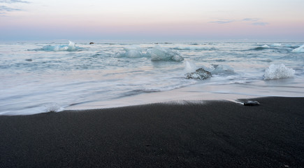 Icy black beach in Iceland called diamond beach during blue hour with pink skies, long exposure photography. Travelling and holiday concept.