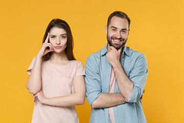 Pensive smiling young couple two friends guy girl in pastel blue casual clothes posing isolated on yellow background. People lifestyle concept. Mock up copy space. Put hand on head, prop up on chin.