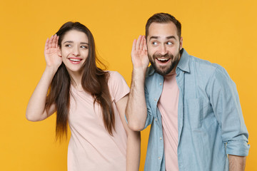 Curious young couple two friends guy girl in pastel blue casual clothes isolated on yellow wall...