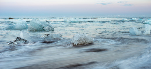 Icy black beach in Iceland called diamond beach during blue hour with pink skies, long exposure photography. Travelling and holiday concept.