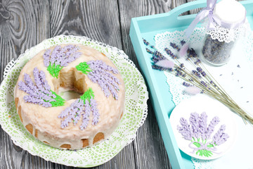 Lavender Cupcake. Sugar coated. Decorated with lavender glaze flowers. Near the bank with lavender inflorescences and a bouquet.