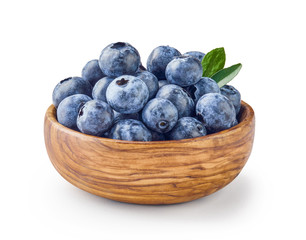 Beautiful blueberries with blueberry leaves in wooden bowl isolated on white background.