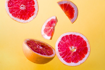 Bright, summer background with different slices of fresh and juicy grapefruit in the air.