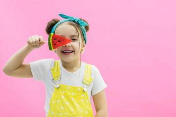 Little model hiding her eye behind watermelon lollipop.