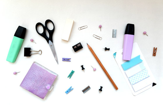 Flatlay stationery composition, writing objects in random order scissors, marker, notepad, paperclip, eraser, pencil, stickers, top view, office and back to school concept