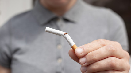 broken cigarette in hand close-up. bad habit, stop smoking, the harm from smoking tobacco and nicotine, concept health