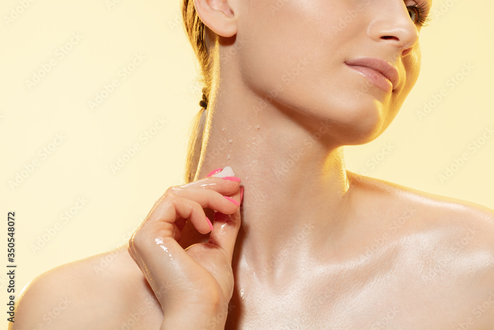 Wall mural close up of beautiful young woman with melting ice cube on yellow background. concept of cosmetics, 