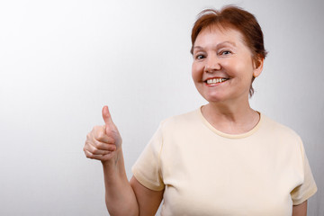beautiful senior woman looks in surprise at the frame on a white background in a light T-shirt....