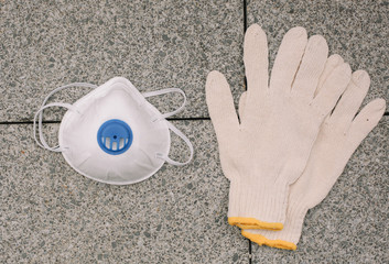 Mask, gloves are lying on the grey table background. Glass of water is standing on the grey background. Safety.