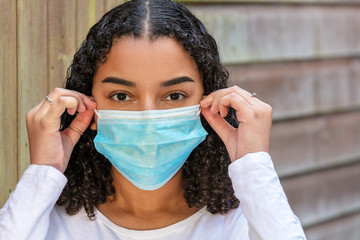 Mixed Race Teenager Girl Woman Wearing fitting or Adjusting Coronavirus COVID-19 Face Mask