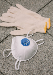 Mask, gloves are lying on the grey table background. Glass of water is standing on the grey background. Safety.
