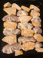 Sliced pieces of raw turkey or chicken breast and ripe pumpkin covered with sour cream sauce with seasonings prepared for baking in the oven. The recipe of a delicious and healthy food. Step by step