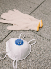 Mask, gloves are lying on the grey table background. Glass of water is standing on the grey background. Safety.