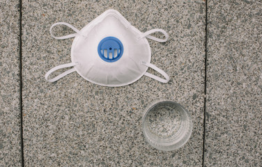 Mask, gloves are lying on the grey table background. Glass of water is standing on the grey background. Safety.
