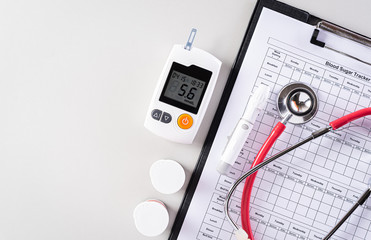 World diabetes day concept,  Blood drop examination tool kit, Red heart, blood sugar tracker record with stethoscope on gray bacckground.