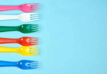 Multicolored plastic dishes on a blue background. The concept of environmental pollution by plastic, ecolog place for text, flat lay