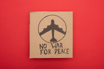 top view of cardboard placard with no war fro peace lettering and airplane on red background