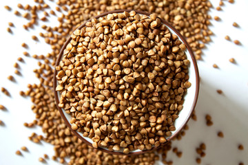 Buckwheat groats in a bowl and around on a white background