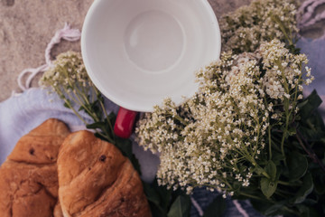 
Beach picnic: big cup, croissants, white wildflowers