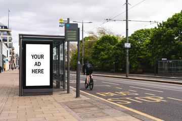 Empty advertising light box. Billboard on a bus stop. Your ad. Cyclist on background