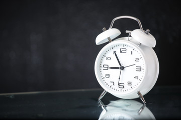 white retro alarm clock in a black background under the water drops.. Morning. Break. Motivation....