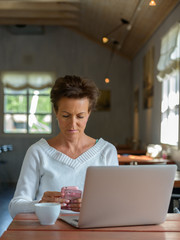 Obraz na płótnie Canvas Mature beautiful woman using phone and laptop inside coffee shop