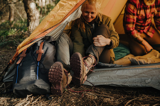 Senior woman taking off hiking shoes sitting in tent