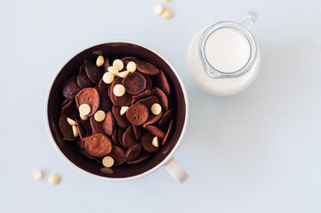 Chocolate tiny pancake cereal with white chocolate in a bowl and milk.