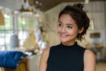 Face of happy young beautiful Asian tourist woman thinking inside coffee shop