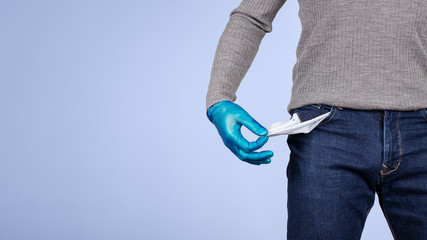 Male half body view. A hand protected by surgical gloves shows the pocket of his empty pants. Concept of crisis and economic recession caused by coronavirus and covid-19.