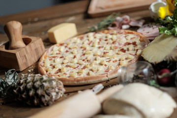 Pizza Hawaiian with a pineapple with ingredient on the wooden table in rustik style