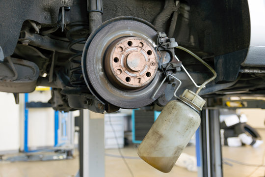 Car repair in a car service. Replacing brake fluid on a vehicle. The brake disc and a special tool against the background of a repair shop.