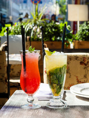 Two cold lemonade strawberries and a mint Mojito. Drink with ice. The glasses are on the table. Summer terrace. Alcoholic and non-alcoholic beverages. Menu for bars, cafes and restaurants. Vegetarian.