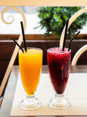 Two cold lemonades orange and blackcurrant . Drink with ice. The glasses are on the table. Summer terrace. Menu for bars, cafes and restaurants. Vegetarian.