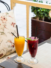 Two cold lemonades orange and blackcurrant . Drink with ice. The glasses are on the table. Summer terrace. Menu for bars, cafes and restaurants. Vegetarian.