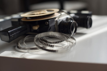 Film reel roll with movie camera and movie clapper on a light table.