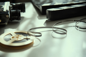 Unwound 8mm film strip on a light background with an old movie camera and clapboard