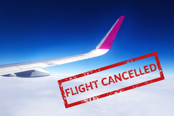 Wing of airplane flying above the clouds in the sky with text flight cancelled. Flight cancellation due to impact of coronavirus COVID-19. Stay home. Airline crisis. Travel, vacation ban concept.