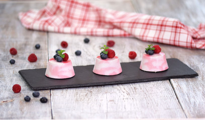 Delicious berry mousse desserts decorated with fresh raspberries, blueberries and mint.