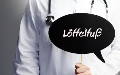 Löffelfuß. Arzt mit Stethoskop hält Sprechblase in Hand. Text steht im Schild. Gesundheitswesen,...