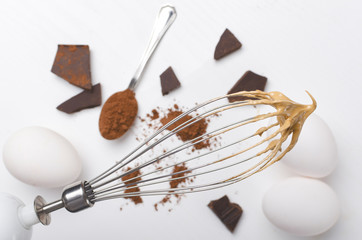 Closeup of whipped chocolate cream on the whisk agaisnt kitchen table.Cooking process, making confections